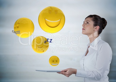 Business woman with tablet looking up at emojis against grey wood panel Business woman with tablet looking up at emojis against grey wood panel