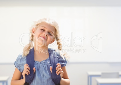 Young girl happy with bag in classroom