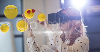 Businesswoman looking at emojis through VR glasses