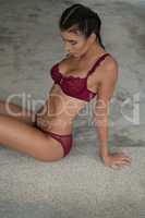 Beautiful woman in burgundy lingerie over concrete background