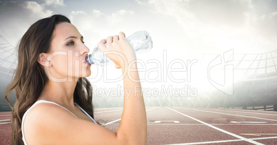 Female runner drinking on track against flares