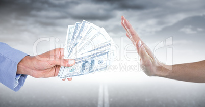 Hand refusing money against road and stormy sky