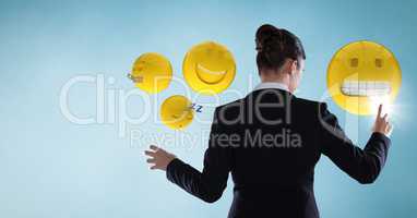 Back of business woman touching emojis against blue background