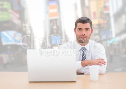 Man with laptop against bright city background