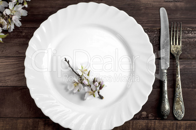 White dish with iron cutlery on a brown wooden surface