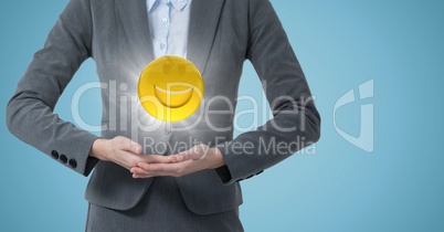 Mid section of business woman with emoji and flare between hands against blue background