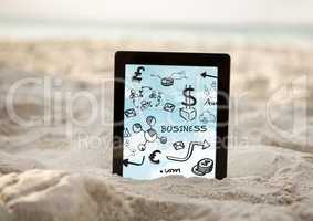 Tablet in sand showing black business doodles and sky