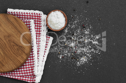 White salt in a wooden bowl on a black surface