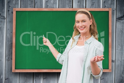 Portrait of happy female student standing against chalkboard