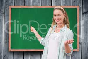 Portrait of happy female student standing against chalkboard