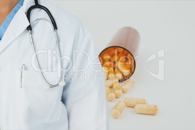 Midsection of doctor with pill bottle