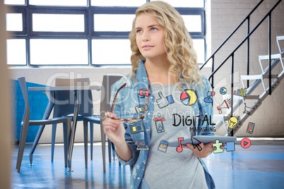 Businesswoman holding tablet PC surrounded by digital marketing text and icons