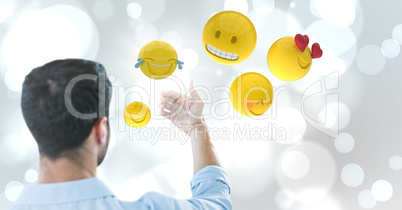Back of man holding up glass device against white bokeh with emojis and flare