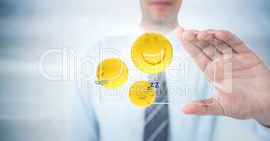 Business man mid section with glass device and emojis with flares against blurry grey wood panel