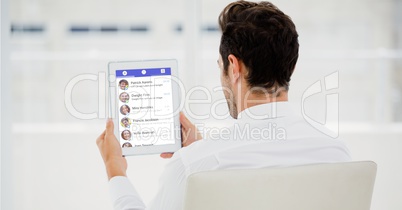 Rear view of businessman using social site on tablet PC