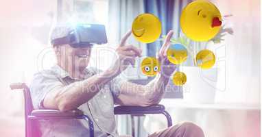 Digitally generated image of emojis flying against man using VR glasses sitting on wheelchair