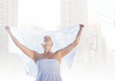 Woman feeling freedom and peace with white sheet in white city with open arms