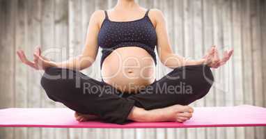 Pregnant woman meditating against blurry wood panel