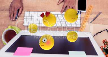 Close-up of hands using computer with emojis at desk
