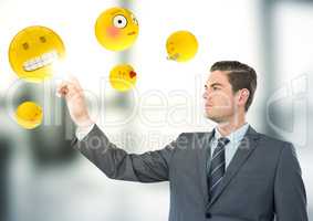 Business man pointing at emojis against blurry grey office