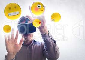 Man in VR with hands up touching flares and emojis against white wall