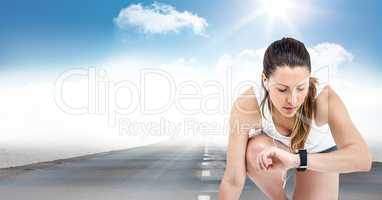 Female runner with headphones on road against sky and sun