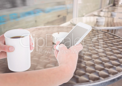 hands with phone and coffee in a terrace