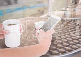 hands with phone and coffee in a terrace