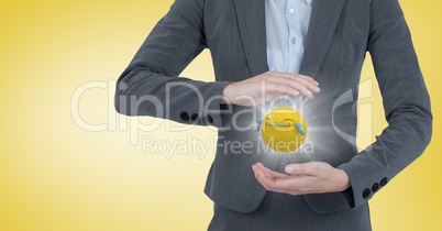 Business woman mid section with emoji between hands and flare against yellow background