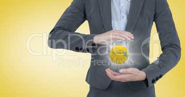 Business woman mid section with emoji between hands and flare against yellow background