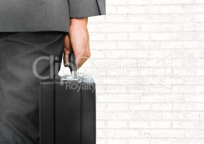 Businessman with briefcase facing white wall