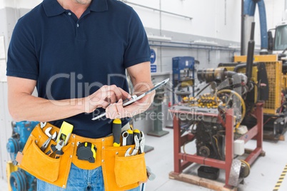 Midsection of handyman using tablet PC at workshop