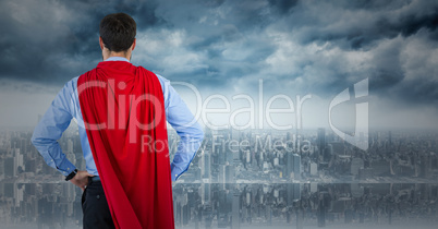 Back of business man superhero with hands on hips against skyline