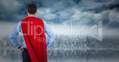 Back of business man superhero with hands on hips against skyline