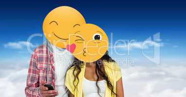 Couple with smiling and kissing emojis on faces using smart phone