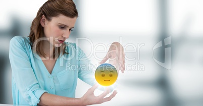 Woman sitting with emoji and flare between hands against blurry grey window