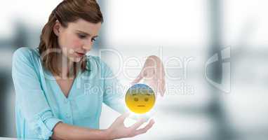 Woman sitting with emoji and flare between hands against blurry grey window