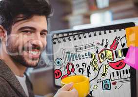 Man with mug sitting at computer showing music doodles on sketchbook