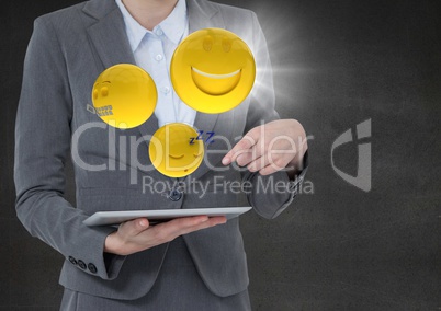 Business woman mid section with tablet and emojis with flare against concrete wall