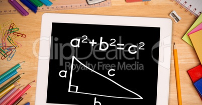 Overhead view of formula in digital tablet with color pencils and school supplies on wooden table