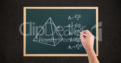 Cropped image of hand writing formulas on blackboard at wooden table