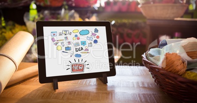 Various icons and text in digital tablet by basket and paper on table