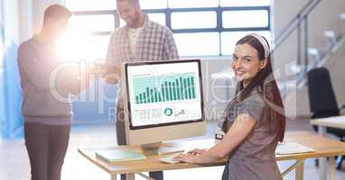 Businesswoman working on graph while colleagues communicating in office