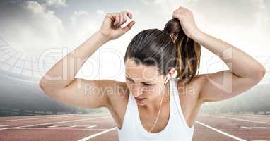 Female runner tying up hair on track against flares