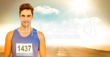 Male runner with number on shirt on road against sky and sun