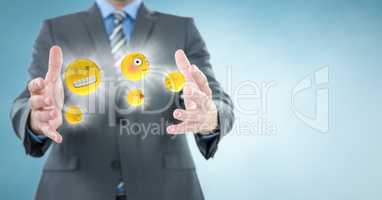 Business man mid section with emojis and flares between hands against blue background