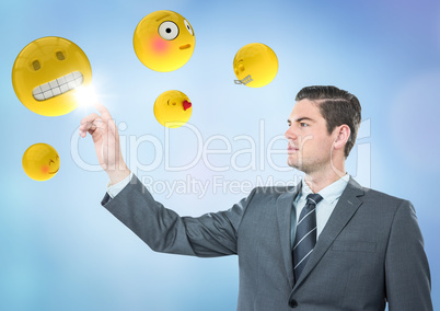 Business man pointing at emojis against blue background Business man pointing at emojis against blue background