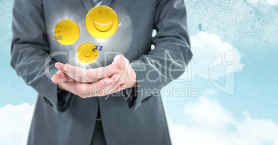 Business man mid section with hands together and emojis with flares against sky