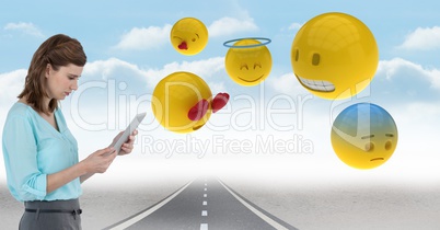 Digital composite image of businesswoman with tablet PC and emojis on street