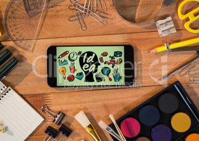 Phone on desk with art supplies showing head doodle against green background
